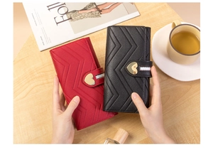 Detail of leather wallets with V-shaped quilting and golden heart metal buckle