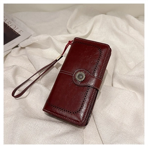 Detail of vintage burgundy oil wax leather wallet with sunflower clasp and wrist strap