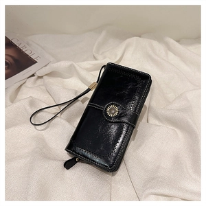 Detail of glossy black oil wax leather wallet with white stitching and daisy clasp