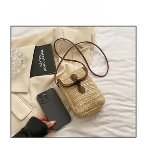 Detail of straw woven crossbody bag with brown leather trim and toggle closure