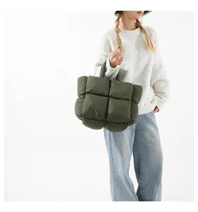 Detailed close-up of dark green quilted puffer tote bag with soft padded fabric texture