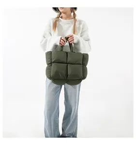 Macro detail of dark green down puffer tote bag featuring square quilted pattern