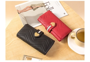 Close-up of elegant V-quilted leather wallets with golden heart clasps in black and red