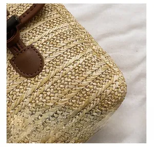 Detail of woven straw bag showing natural texture, brown leather trim and bamboo twist lock
