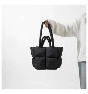 Close-up of black quilted puffer tote bag with glossy finish and soft padded square texture