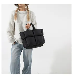 Close-up of black quilted puffer tote bag with large square stitching and soft padded handle