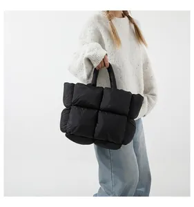 Chic quilted down tote bag in black, styled with casual wear in a minimalist studio