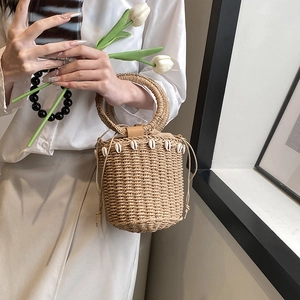 Handmade straw bucket bag with seashell decor and round handles for summer beach vacations