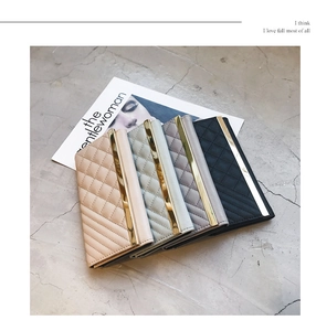 Flat lay of long quilted wallets in pink, blue, grey and black with gold accents