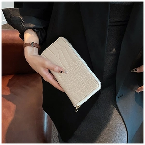 Close-up of beige crocodile pattern long wallet with elegant golden zipper detail