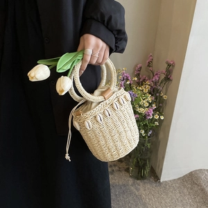 Straw bucket bag with seashell trim and drawstring lining for summer beach vacation