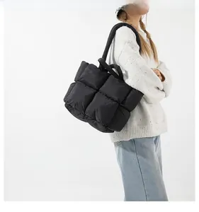 Detail of black quilted puffer tote bag showing padded texture and wide shoulder strap