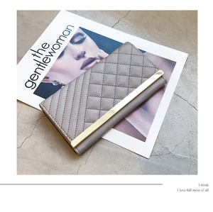Detailed close-up of gray long wallet with quilted pattern and gold metal trim