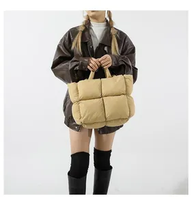 Detail of beige quilted puffer tote bag with large square stitching and padded handle
