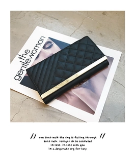 Detail of black quilted long wallet with elegant diamond pattern and gold metal accent