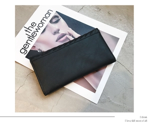 Close-up of black leather long wallet with V-shaped quilting on a fashion magazine