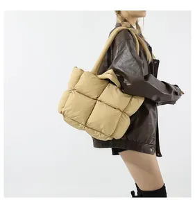 Close-up of khaki quilted tote bag featuring large square puffer patterns and wide straps