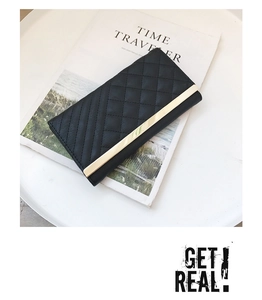 Detailed close-up of a black quilted long wallet featuring gold metal trim on a tray