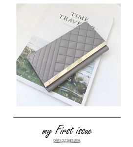 Macro shot of grey quilted wallet featuring a sleek gold metal trim and elegant stitching