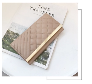Close-up of elegant beige quilted long wallet for women with gold metal bar accent