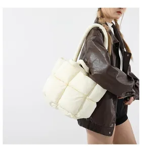 Detailed view of cream puffer tote bag showing padded woven texture and shoulder strap