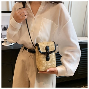 Detail of hand-woven straw phone bag with black leather piping and unique wooden clasp
