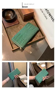 Detail of green crocodile embossed long wallet with metallic zipper and premium texture
