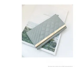 Detail view of light grey quilted leather wallet featuring a stylish gold metal bar clasp