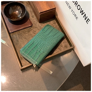Close-up of a green crocodile texture leather wallet with golden metal zipper closure