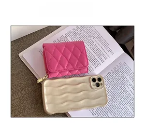 Mini magenta quilted leather wallet with gold zipper compared to a phone case for size