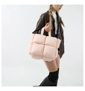 Detailed side view of light pink quilted puffer tote bag styled with a leather jacket