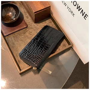 Macro view of black crocodile pattern patent leather wallet with gold metal zipper
