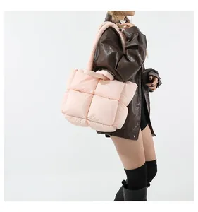 Close-up of a light pink quilted tote bag showing square stitching and soft padded texture