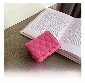 Detail of rose pink quilted leather mini wallet with gold zipper on vintage book