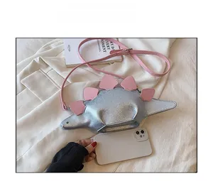 Mini dinosaur shaped crossbody bag in silver and pink compared with a smartphone