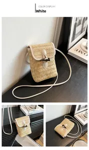 Detail of a woven straw crossbody bag in cream white with a vintage wooden horn buckle