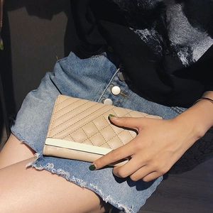 Chic beige quilted long wallet with metallic bar detail held in a lifestyle setting
