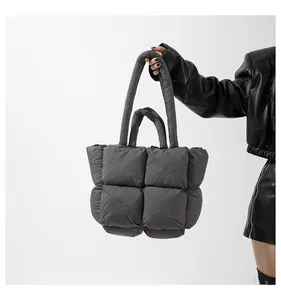 Detail of grey quilted down tote bag with soft padded handles and square puff texture