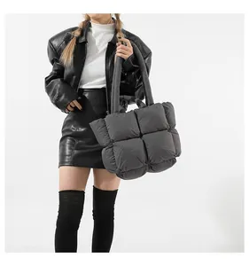 Fashionable dark grey quilted down tote bag worn with a stylish leather jacket