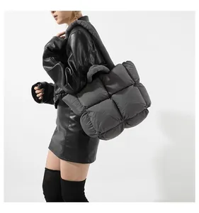 Side view of dark grey quilted down tote bag with oversized check padding on a model