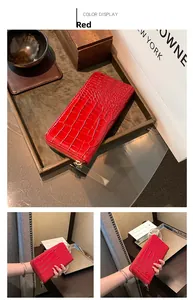 Detail of red crocodile textured long wallet with golden zipper and luxury finish