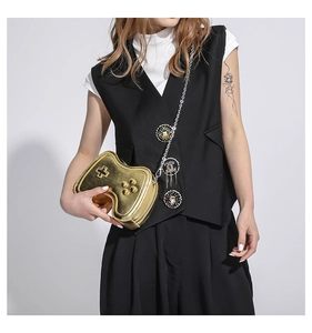 Detail of creative golden game controller shaped crossbody bag with metallic badges