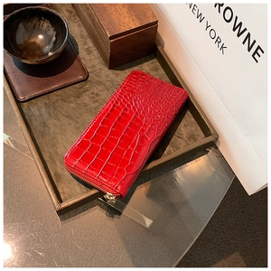 Detail of red crocodile embossed leather long wallet with premium gold zipper closure