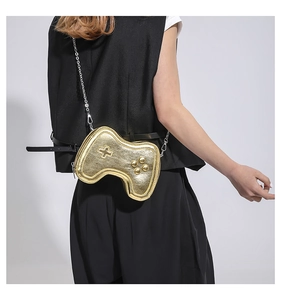 Detail of a golden game controller shaped crossbody bag with a silver chain strap