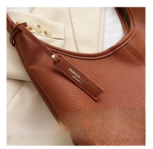 Dettaglio macro della borsa tote in pelle marrone con etichetta e finiture metalliche