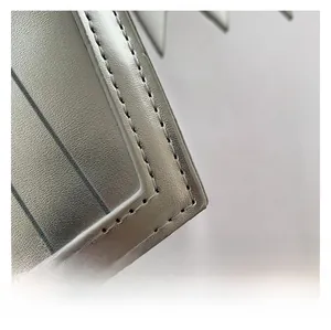 Detail of silver metallic textured fabric with precise grey double stitching on bag