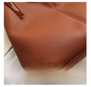 Dettaglio della trama della pelle con motivo litchi e etichetta laterale su borsa marrone