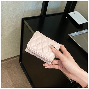 Close-up of pink quilted accordion card holder with gold zipper held in hand