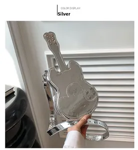 Detail of silver guitar-shaped crossbody bag with metallic studs and mirror finish