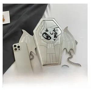 Detail view of silver coffin-shaped crossbody bag with bat wings and a phone for scale
